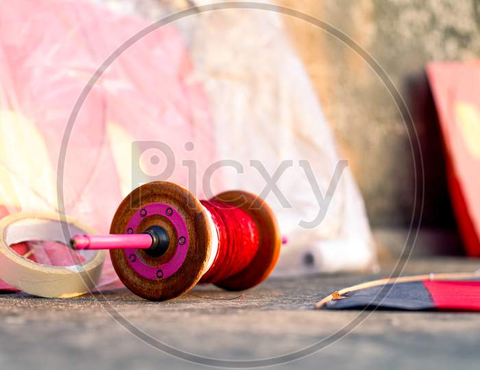 Series Of Colorful Red Yellow Paper And Wood Kits Placed Near Fikri Charki Spools Filled With Dor Plain Thread And Manjha Glass Covered Thread For The Indian Festival Of Makar Sankranti Uttarayana