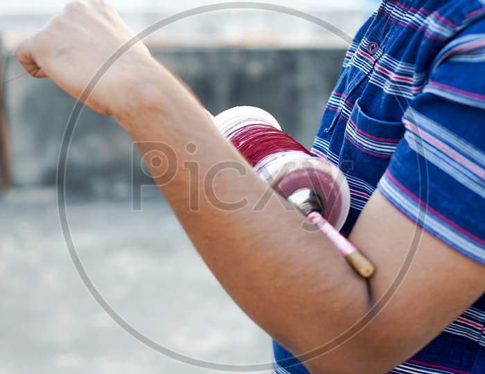 Man Holding A Charki Phirki Thread Spool In The Crook Of His Elbow And Winding It With The Other Hand To Ensure Taughtness For The Famed Kite Fighting Festival Of Makar Sankranti Uttarayana