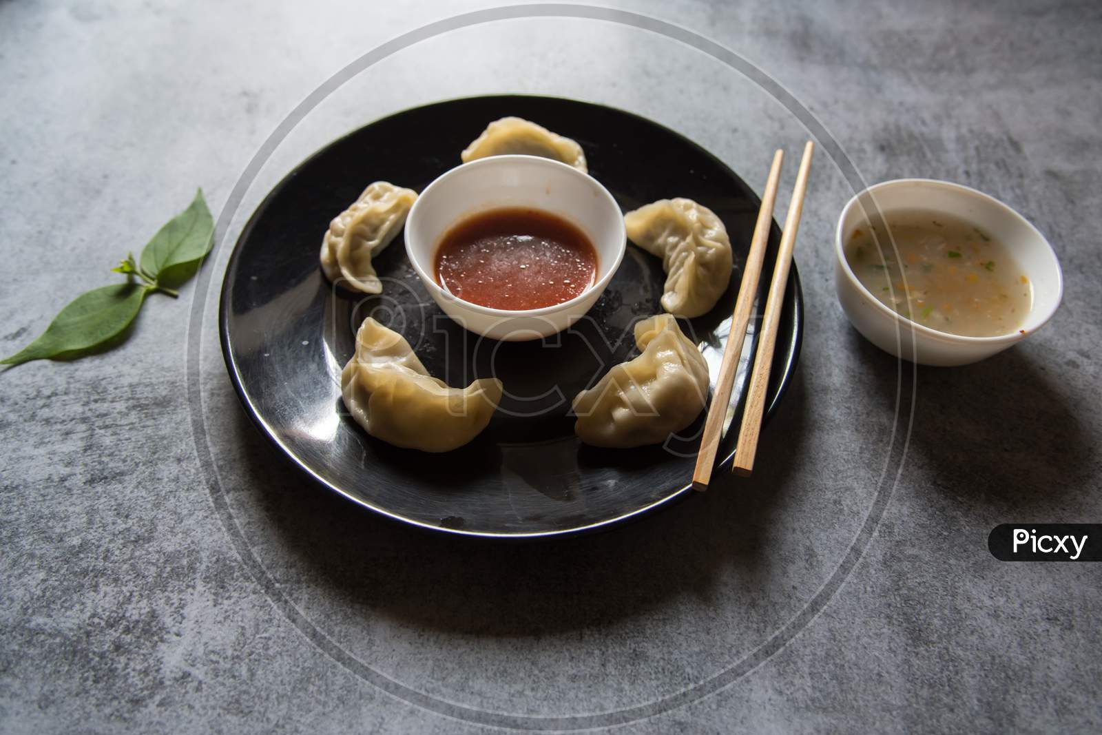 Close up of   Popular snacks  momos on a black plate along with condiments