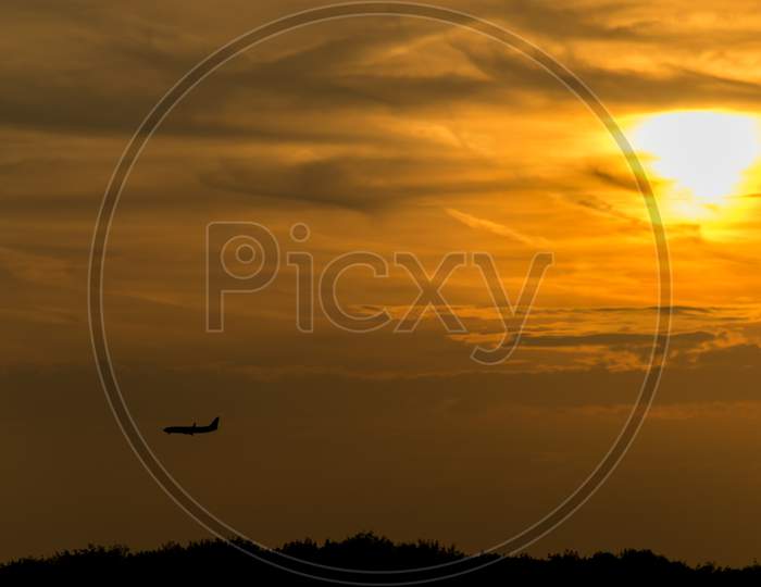 Silhouette Of A Landing Airplane Against Sunset In Amsterdam, Netherlands