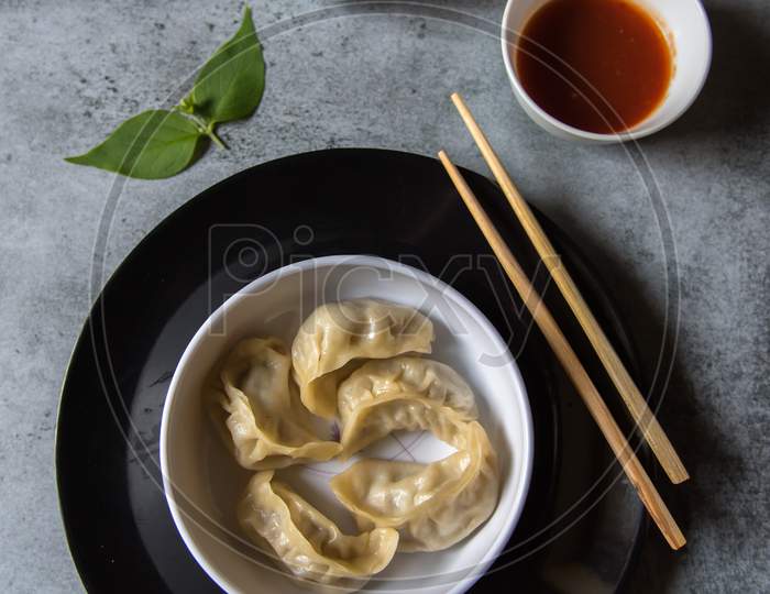 Top view of dim sums in a bowl on a black plate