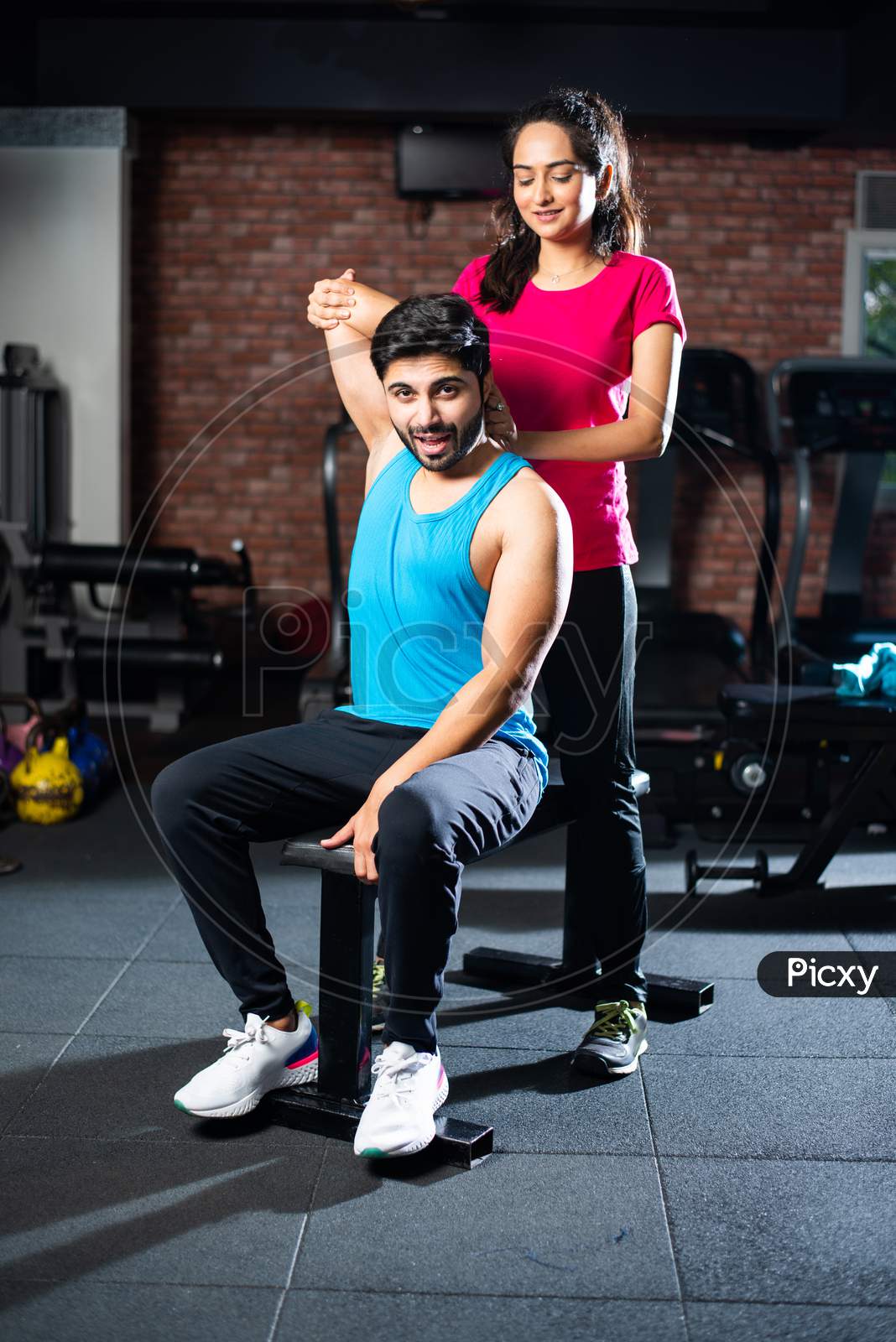 Indian Asian Young Couple Stretching In Gym Post Exercise