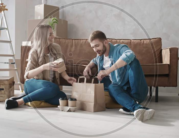 Couple Unpacking Fast Food In Just Moved Home. Couple Having Delivery Food. New Home Delivery. Couple Eating Fast Food At Home. Shot On Red