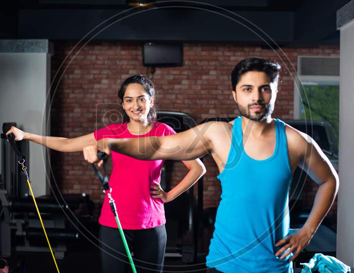 Indian Asian Young Couple Exercising In Gym With Resistance Band