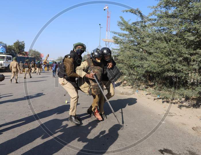 An injured policeman is being is helped out by colleagues after being injured during clash with farmers. Farmers are protesting against new farm laws that they fear will reduce their earnings and give more power to large retailers, at the Delhi-Haryana border in Singhu on November 27, 2020.