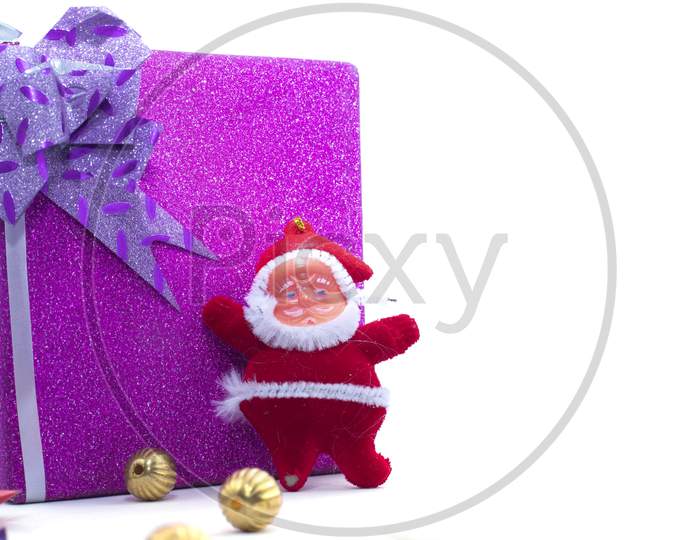 The Statue Of Santa Claus With The Large Gift Box Is Isolated On A White Background