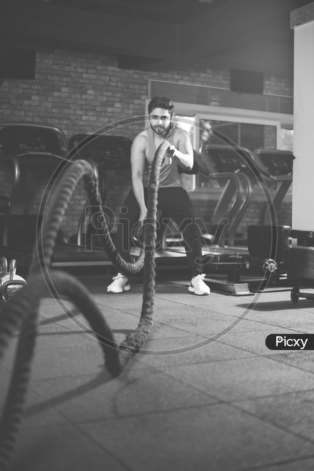 Indian Asian Young Man Exercising With Battle Rope In The Gym