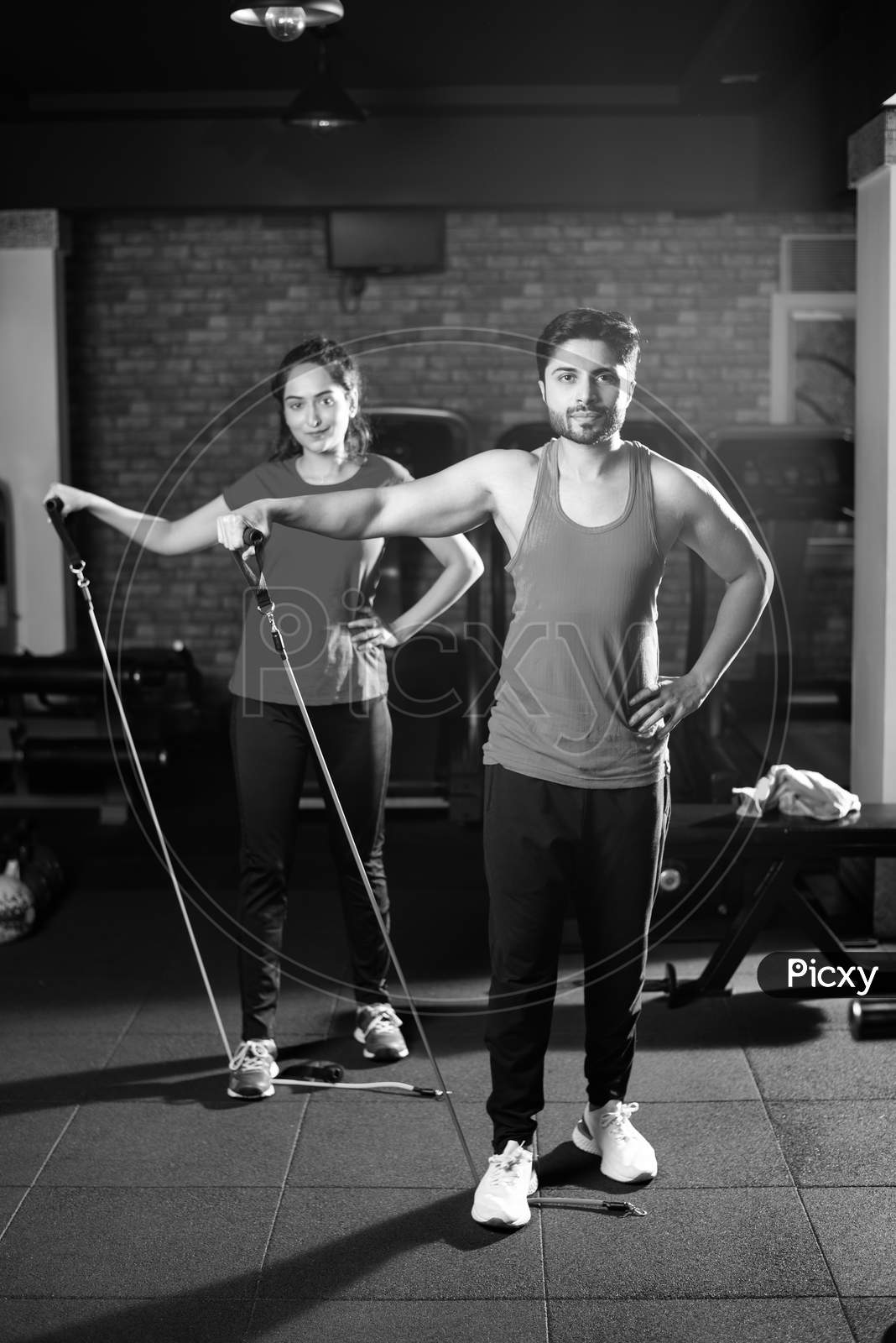 Indian Asian Young Couple Exercising In Gym With Resistance Band