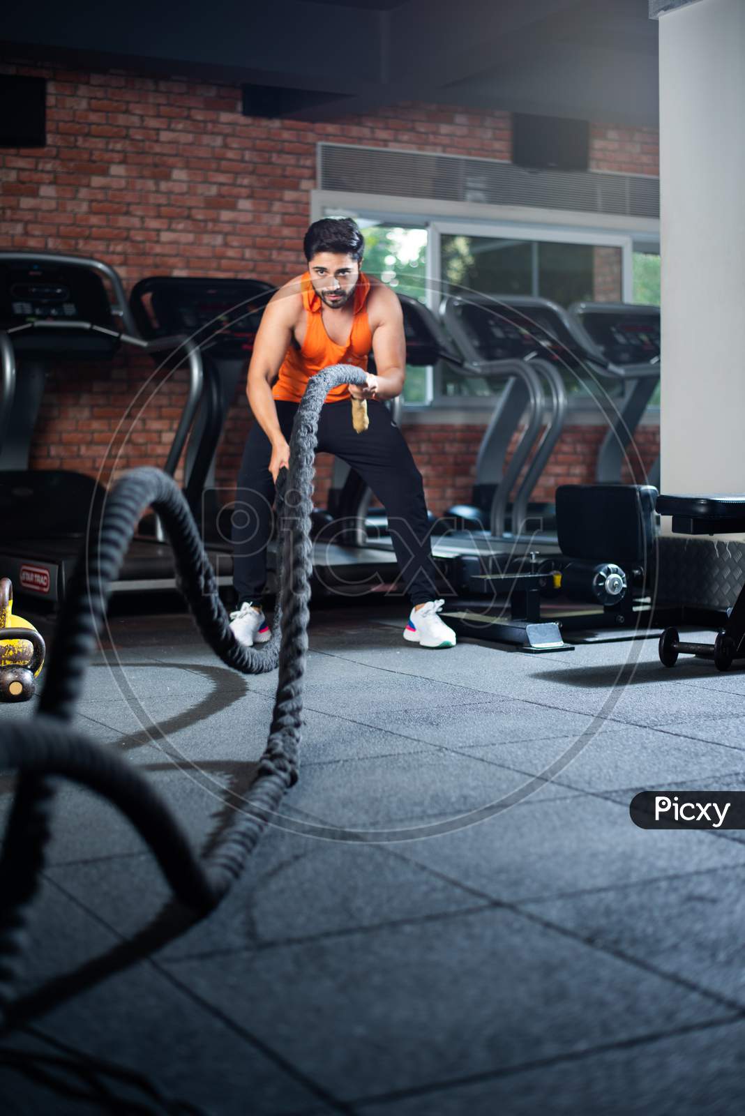 Indian Asian Young Man Exercising With Battle Rope In The Gym
