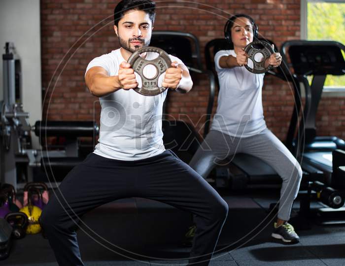 Portrait Of Indian Asian Young Couple Working Out Together In Gym, Training With Fitness Equipments