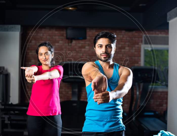 Indian Asian Young Couple Stretching In Gym Post Exercise