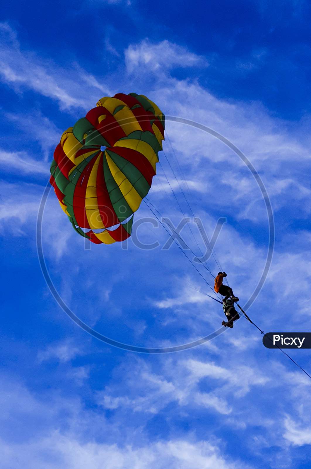 Paraglider in Colorful parashoot in blue sky