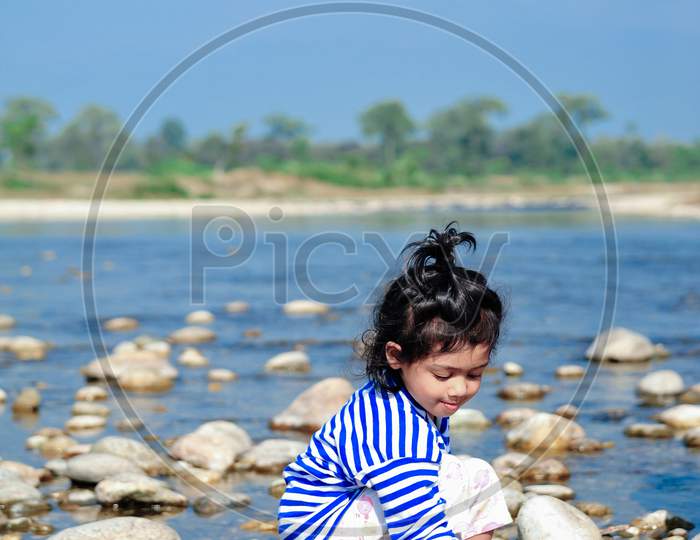 kid sitting on a bank of river