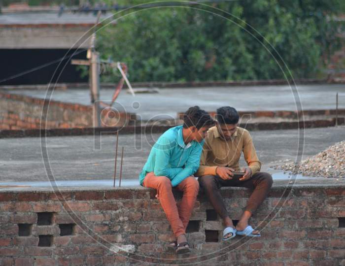 Two boys running mobile phone on terrace