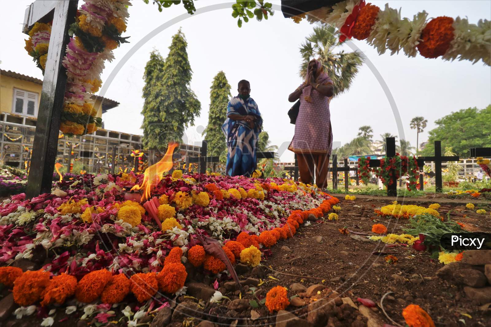 Women pray for a deceased relative at a graveyard on All Souls Day in Mumbai, India, November 2, 2020.