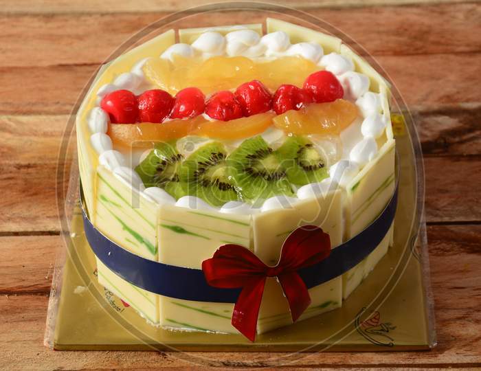 Freshly Made Mix Fruit Cream Cake On Wooden Table. Selective Focus