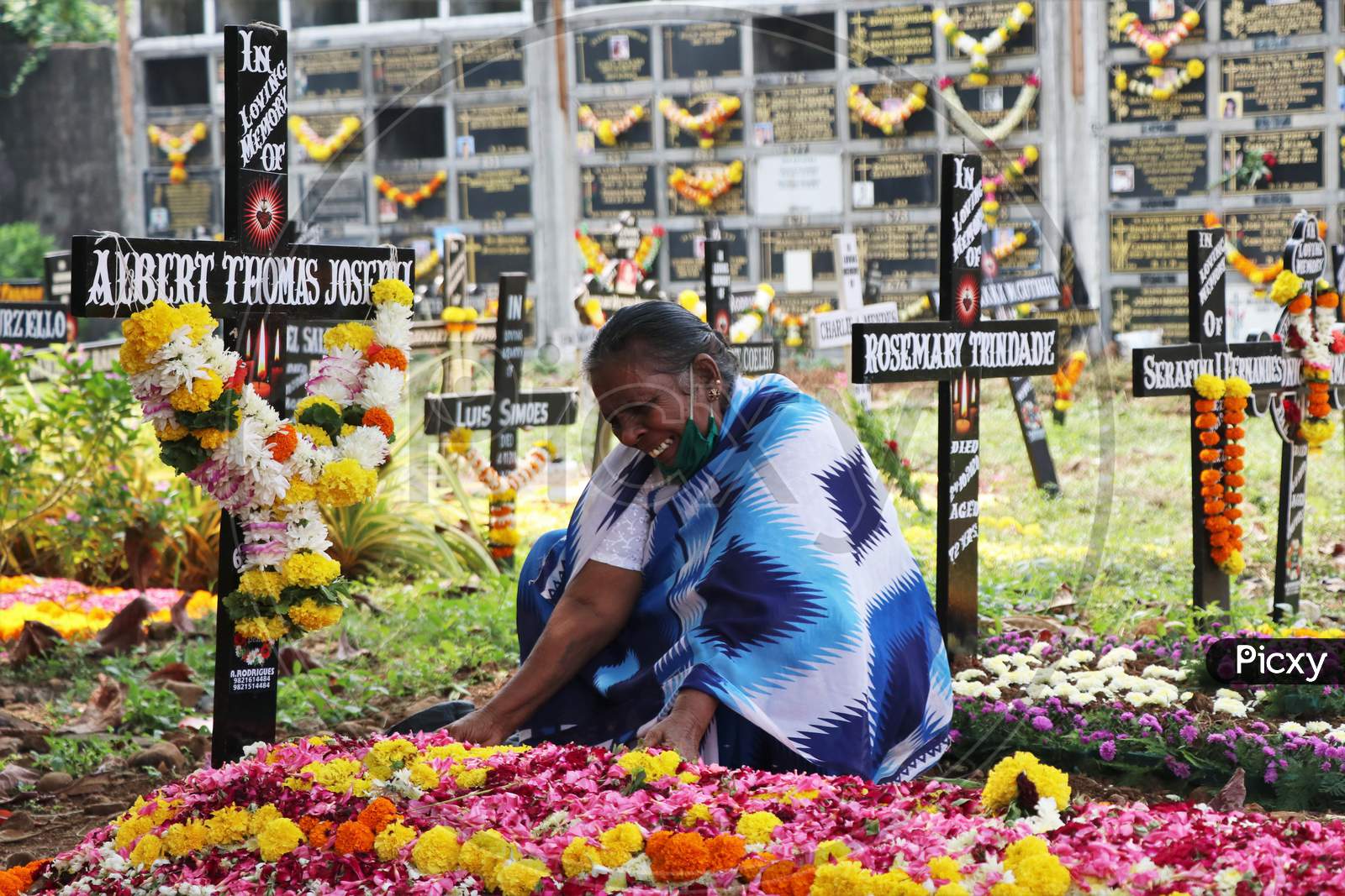 A woman is seen mourning over a deceased relative at a graveyard on All Souls Day in Mumbai, India, November 2, 2020.