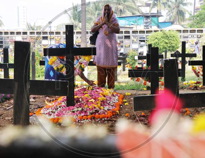 A woman prays for a deceased relative at a graveyard on All Souls Day in Mumbai, India, November 2, 2020.
