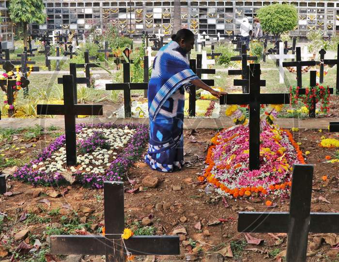 A woman prays for a deceased relative at a graveyard on All Souls Day in Mumbai, India, November 2, 2020.