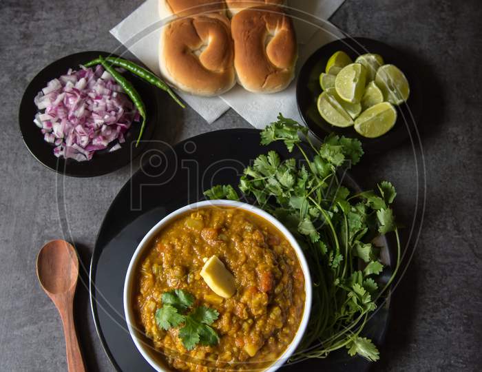 View from top of spicy pav bhaji or masala dish and bread in a bowl on a black plate