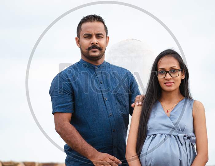 The Pregnant Young Lady And Her Handsome Husband Portrait, Blown-Out White Background, Natural Lighting Conditions In Galle Fort, South Asian Young Couple.