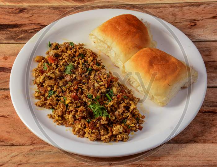Masala Anda Bhurji Or Spicy Indian Scrambled Eggs With Bread Or Bun / Pav, Popular Street Food In Mumbai. Served In White Crockery Over Rustic Wooden Background. Selective Focus