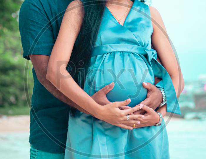 Young Parents Expecting New Baby Holding Mother'S Belly In Both Hands Front Close Up Photograph Under Natural Lights In The Beach Of Galle.