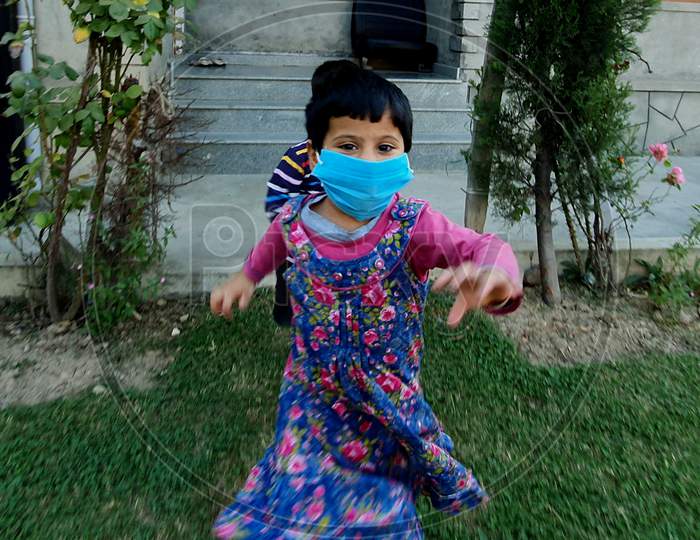 Masked Children Playing Games And Running In A Public Park. Wearing Masks Are Common After Coronavirus Pandemic.