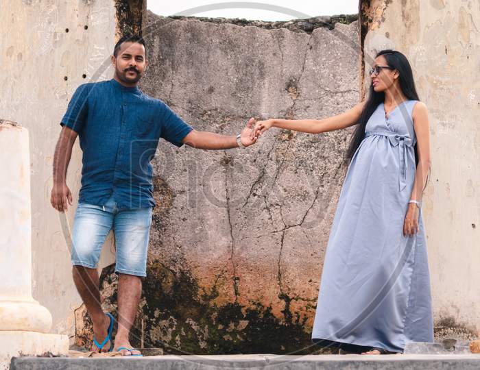 Two Beautiful Models, A Young Married Couple, Mother To Be Pregnant Lady, Holding Hands, And Looking At Her Husband Standing Portrait In Front Of Ruins Of Galle Dutch Fort.