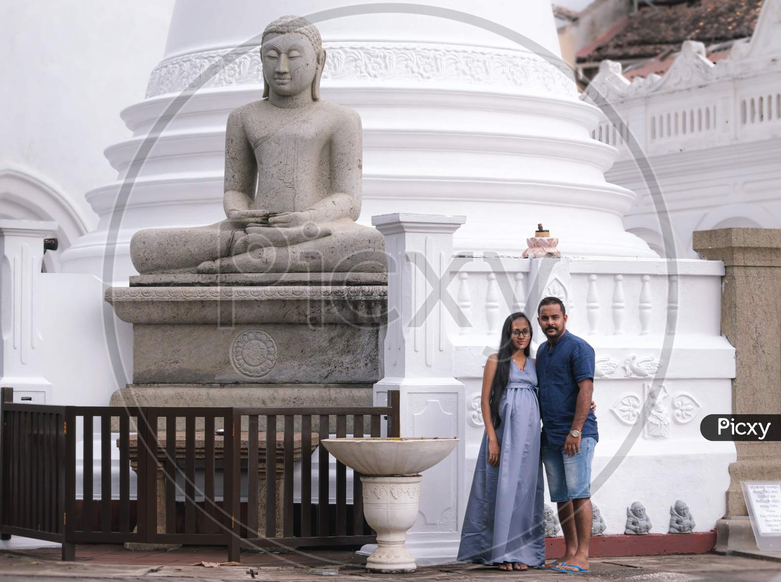 Pregnant Young Women And Her Husband Posing For Portraiture In Front Of Galle Fort Temple, Beautiful Couple Standing Together Close To Each Other.