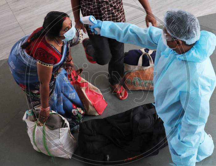 A health worker in personal protective equipment (PPE) checks the temperature of a passenger at a railway station, amid the spread of the coronavirus disease (COVID-19), in Mumbai, India, November, 2020.