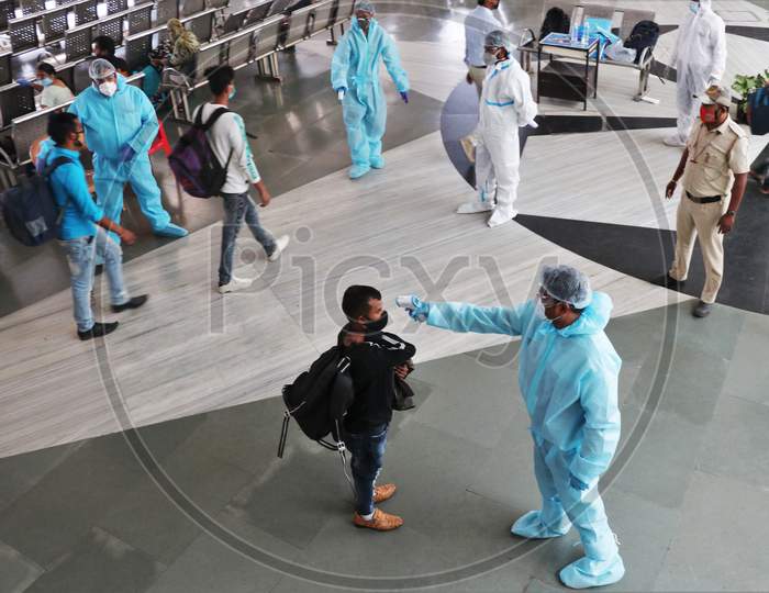 A health worker in personal protective equipment (PPE) checks the temperature of a passenger at a railway station, amid the spread of the coronavirus disease (COVID-19), in Mumbai, India, November, 2020.
