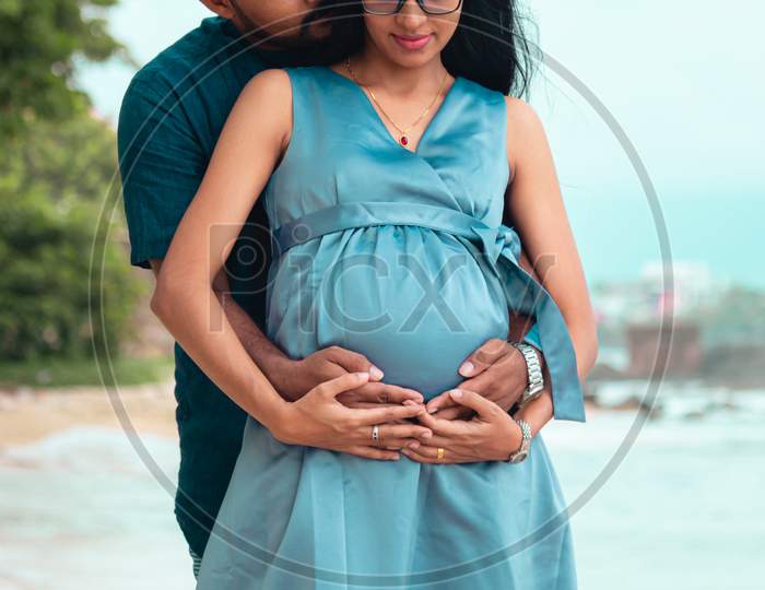 Young Parents Expecting New Baby Holding Mother'S Tummy In Both Hands And Gentle Kiss In The Necks, Front Close Up Photograph Under Natural Lights In The Beach Of Galle.