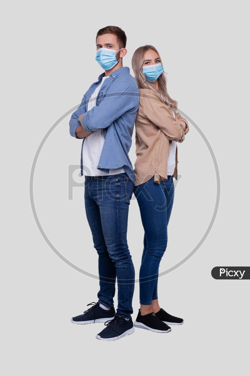 Couple Standing Back To Back Wearing Medical Mask Watching To Camera. Man And Woman, Lovers, Friends, Couple Concept