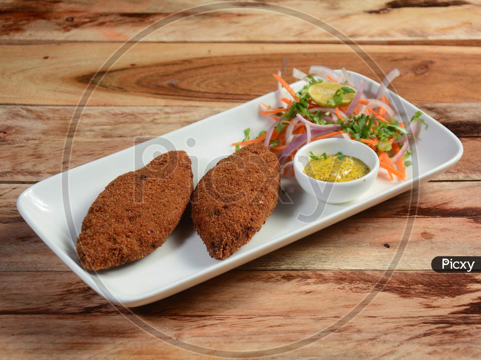 Tasty Crispy Fried Fish Cutlets Served With Chutney, Lemon,Carrot And Onions On A Rustic Wooden Background, Selective Focus