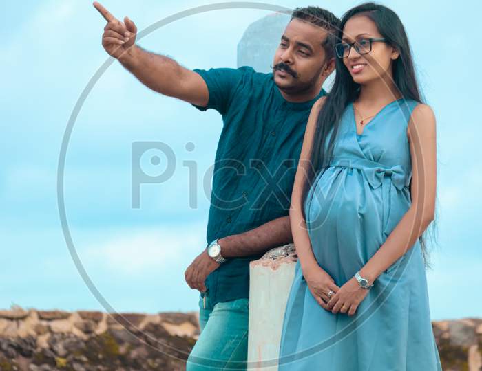 Young Beautiful Married Couple Pose For A Photo In Galle Fort, Planning The Bright New Future With Unborn Child Concept, Father Pointing Out The Direction To The Pregnant Wife