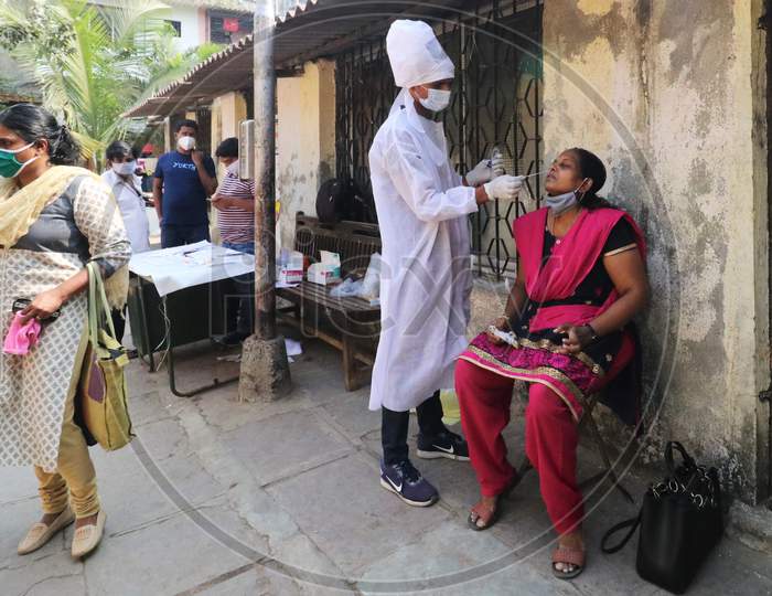 A health worker in personal protective equipment (PPE) collects a swab sample from a woman during a testing campaign for the coronavirus disease (COVID-19), at a clinic in Mumbai, India, November, 2020.