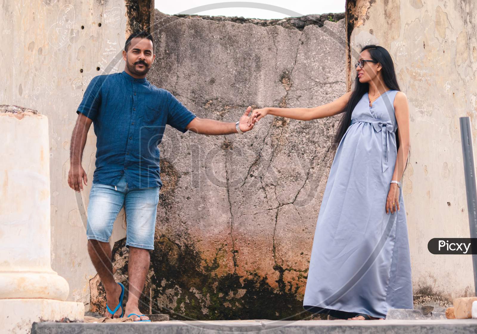 Two Beautiful Models, A Young Married Couple, Mother To Be Pregnant Lady, Holding Hands, And Looking At Her Husband Standing Portrait In Front Of Ruins Of Galle Dutch Fort.