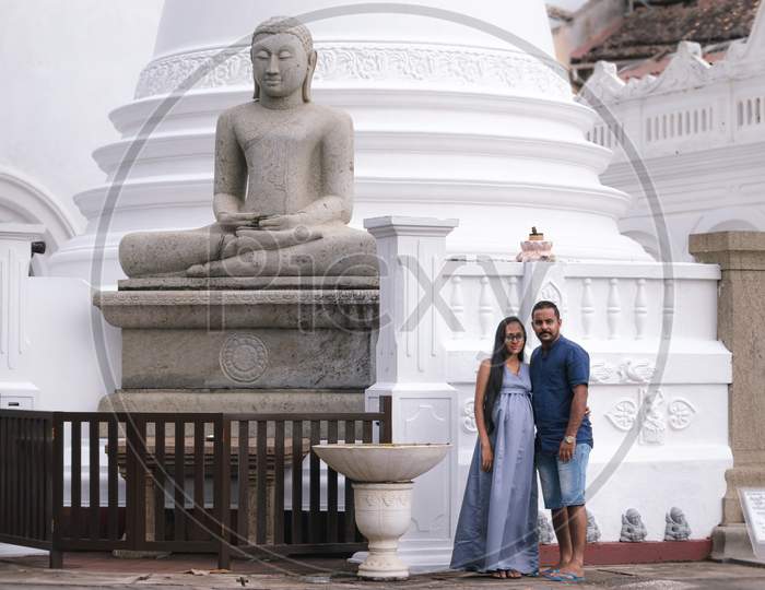 Pregnant Young Women And Her Husband Posing For Portraiture In Front Of Galle Fort Temple, Beautiful Couple Standing Together Close To Each Other.
