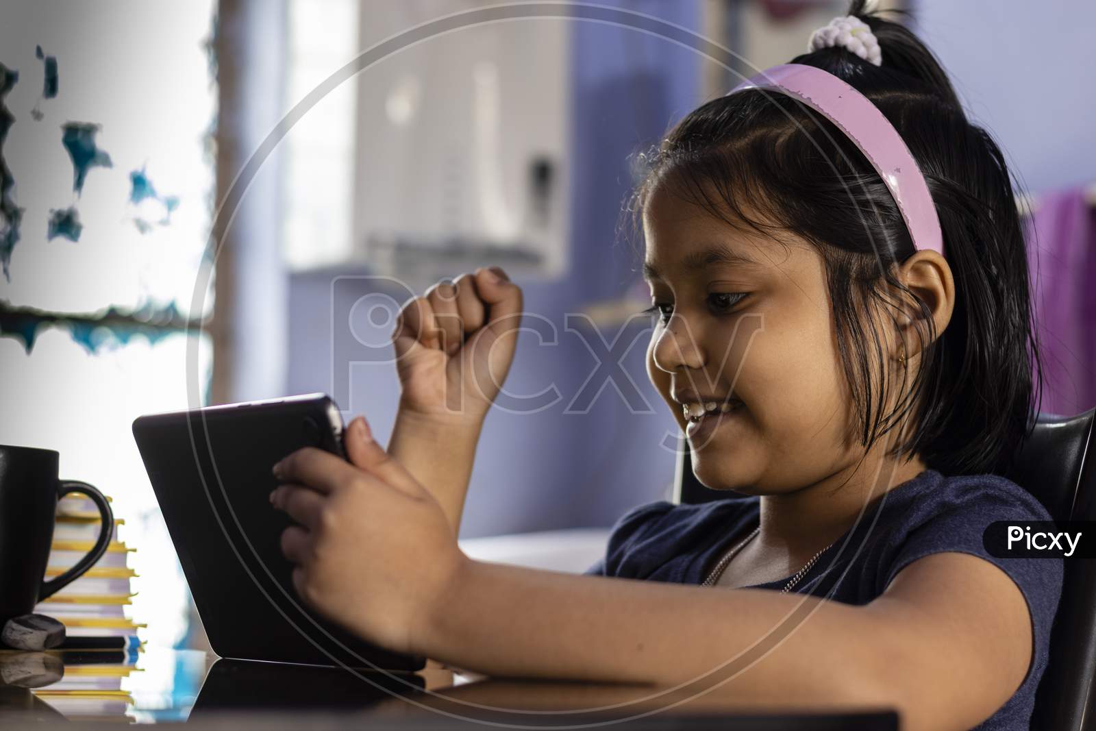 Image of An Indian Cute Girl Child Playing Video Games At Home With  Tablet-HF435710-Picxy