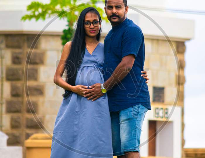Lovely Sri Lankan Smiling Couple Close To Each Other In Front Of Galle Fort Lighthouse, Evening Portrait, The Expectation Of A Baby, Holding On To Her Belly