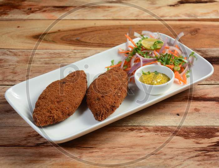 Tasty Crispy Fried Fish Cutlets Served With Chutney, Lemon,Carrot And Onions On A Rustic Wooden Background, Selective Focus