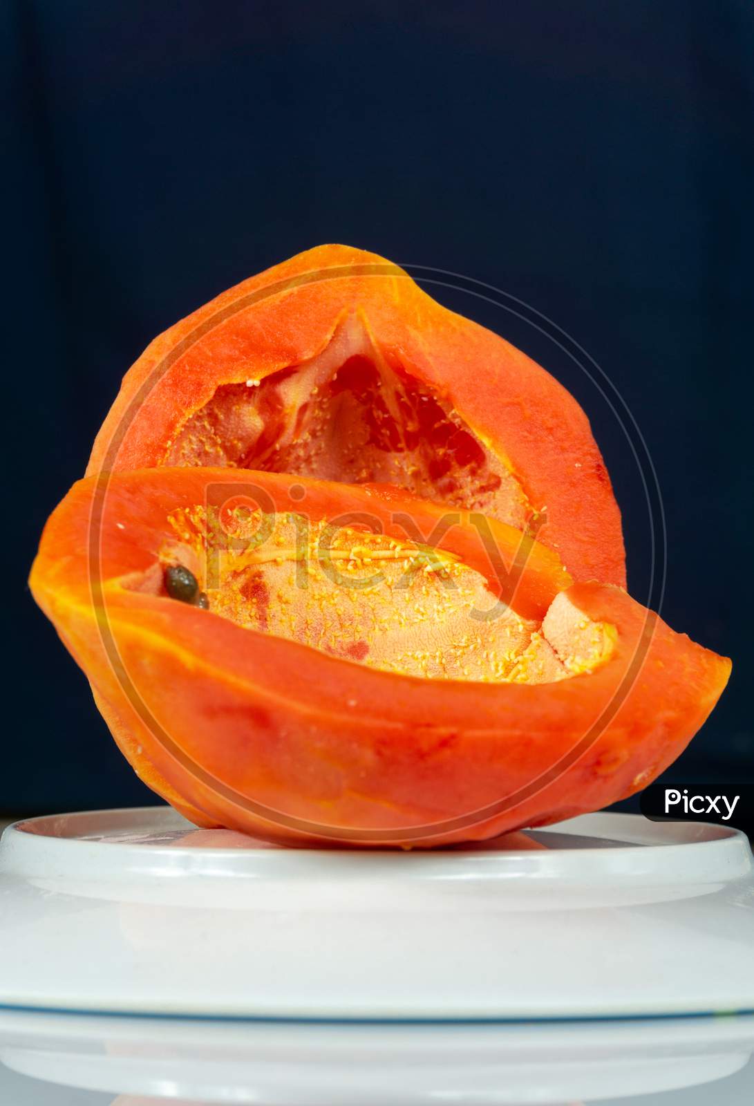 Fresh Papaya Cut Into Two Pieces Kept On A Plate