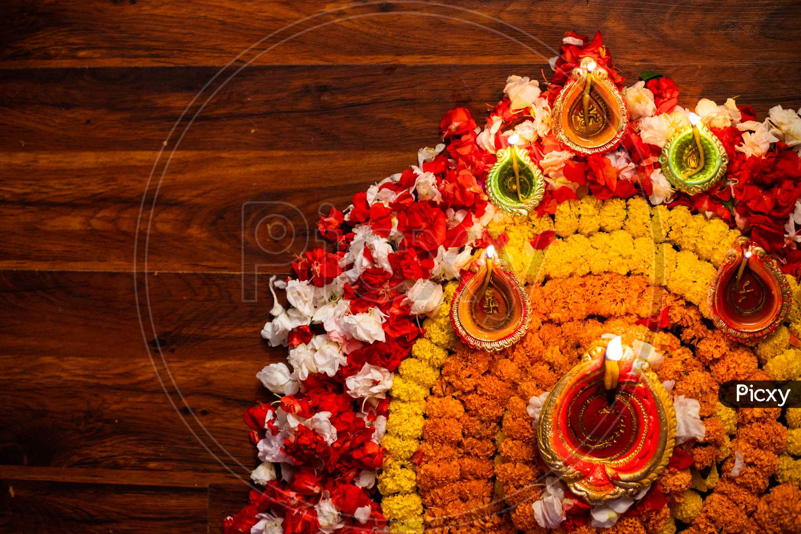 Diwali celebration - Diya oil lamps lit on colorful rangoli of flowers