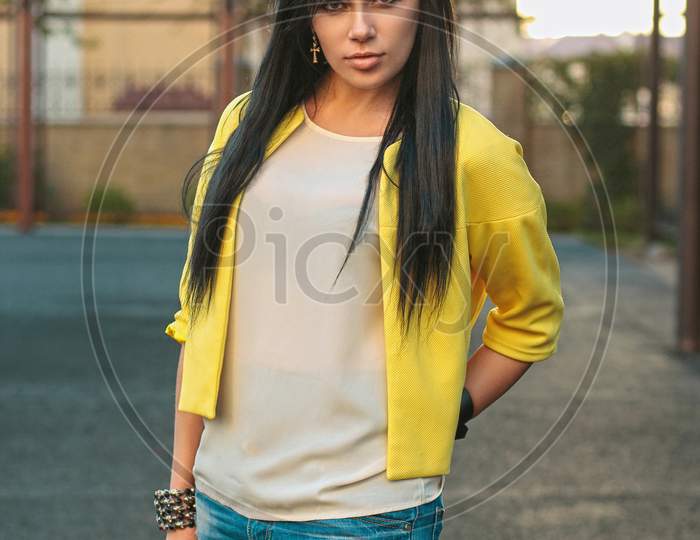Beautiful Girl In A Yellow Jacket And Jeans Holds Glasses