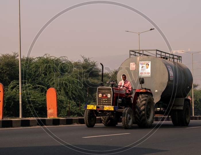 A tractor carrying a water tanker on national highway