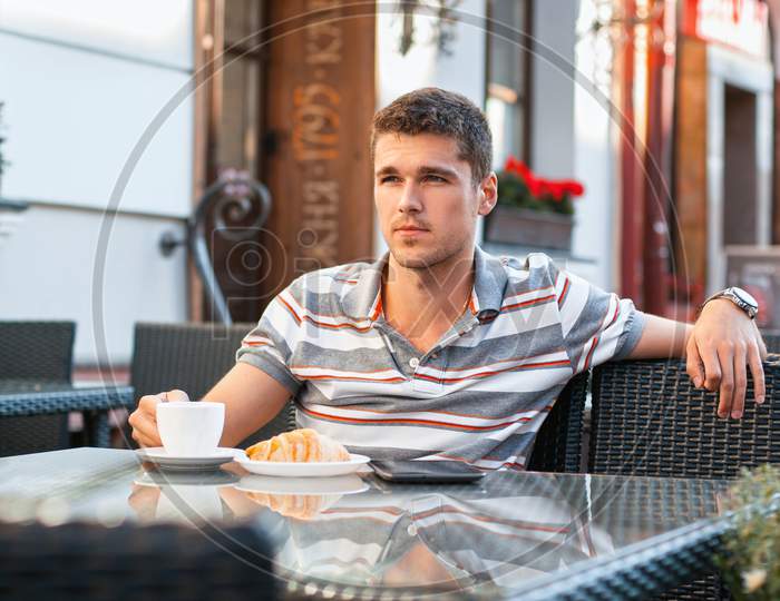 Young Man Drinking Coffee With Croissant
