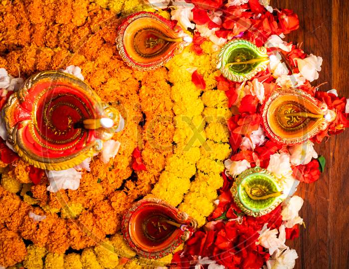 Diwali celebration - Diya oil lamps lit on colorful rangoli of flowers