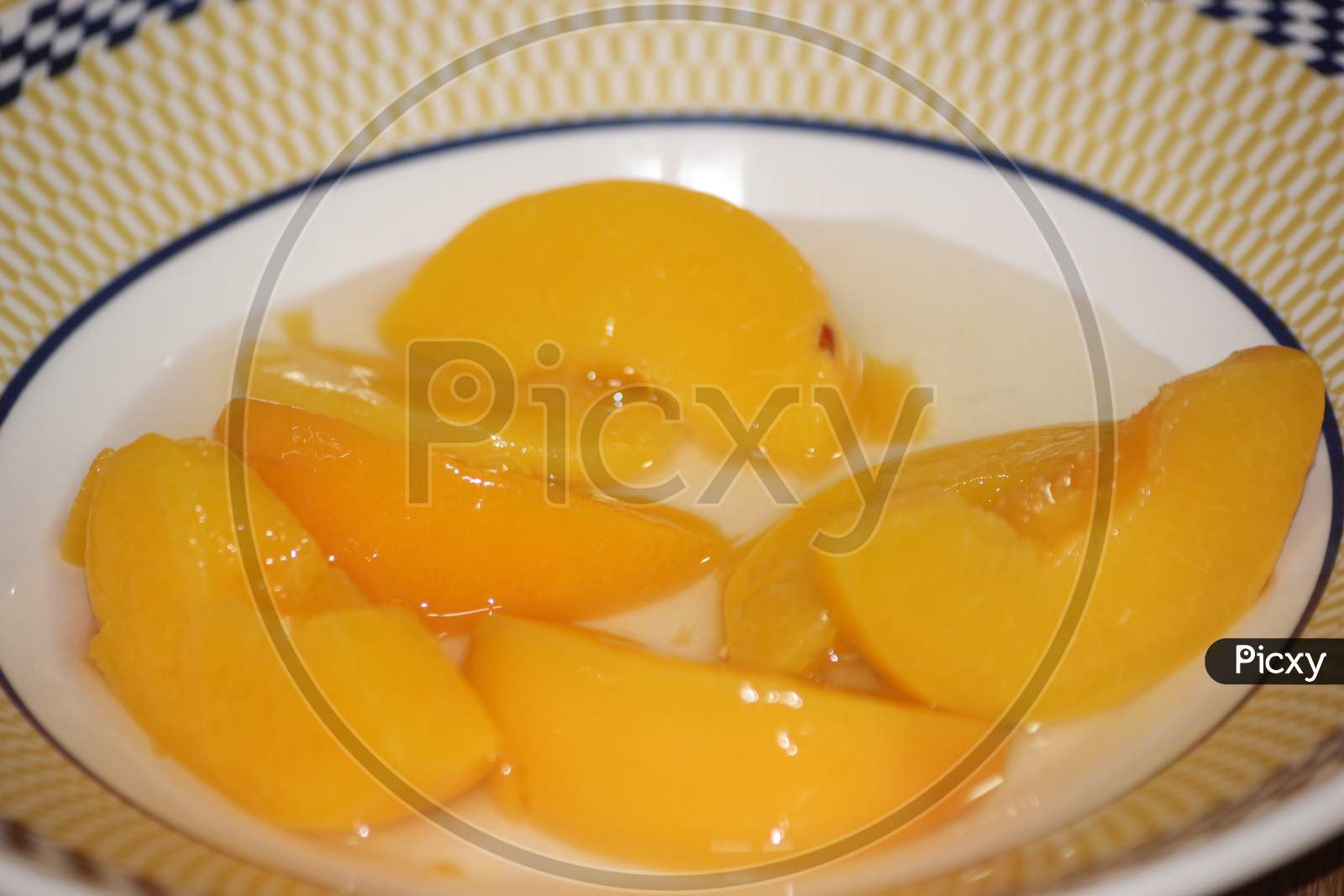 Canned Peaches Halves Sprinkled With Syrup In White Plate.