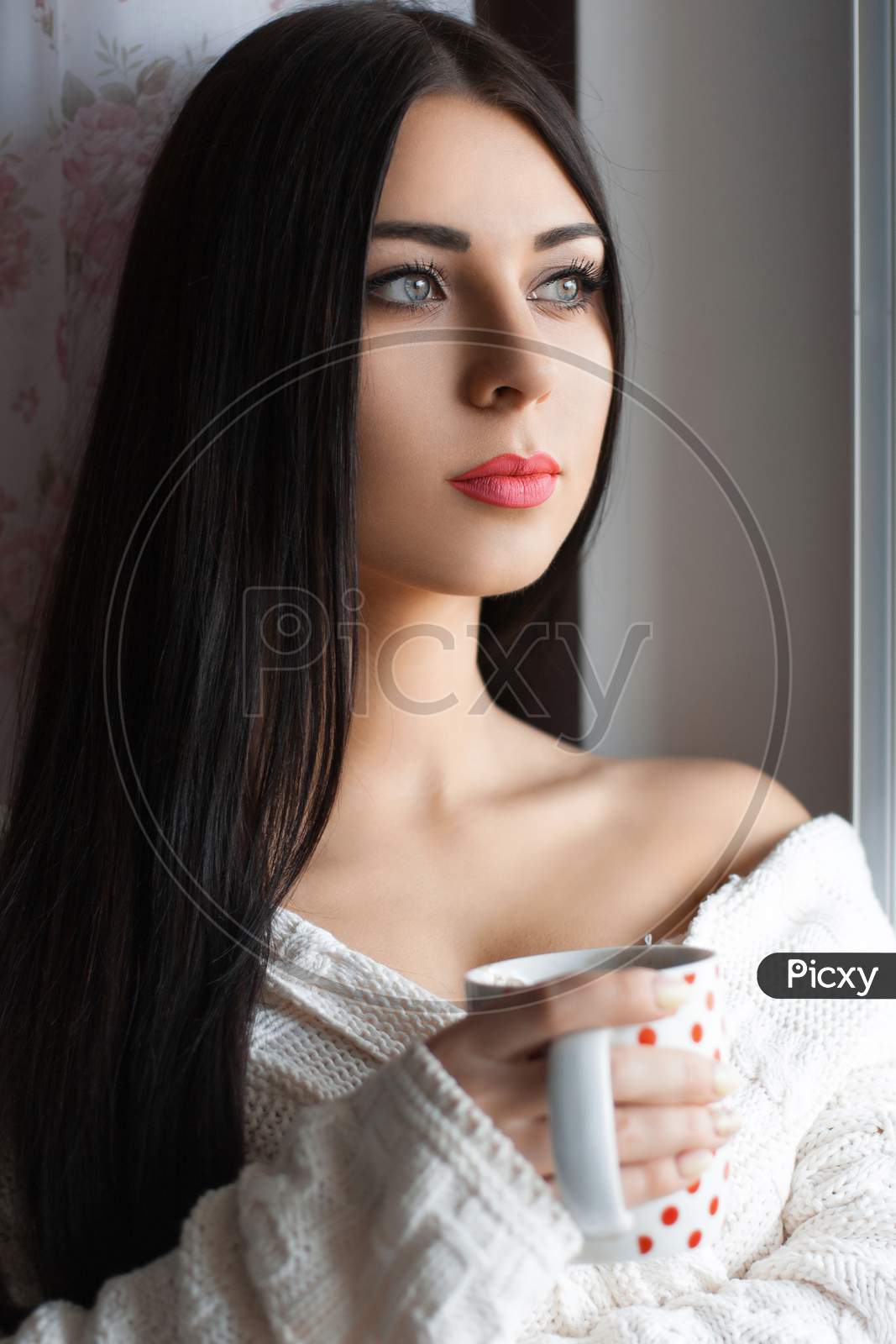Beautiful Girl With Long Hair Drinking Coffee By The Window